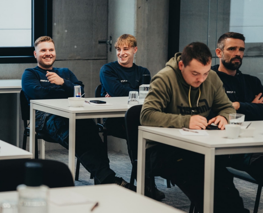 Vier mannen zitten aan tafels tijdens een opleiding.